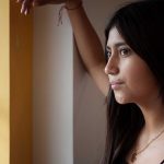 Joven latina mirando por una ventana