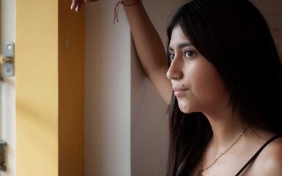 Joven latina mirando por una ventana