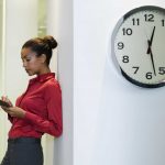 trabajadora junto a reloj en la oficina