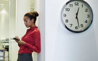 trabajadora junto a reloj en la oficina
